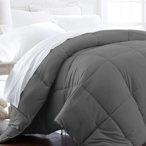 Grey quilted comforter by Beckham Hotel Collection draped over a bed with white sheets in a bright bedroom